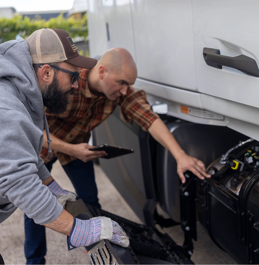 Two men examining truck components