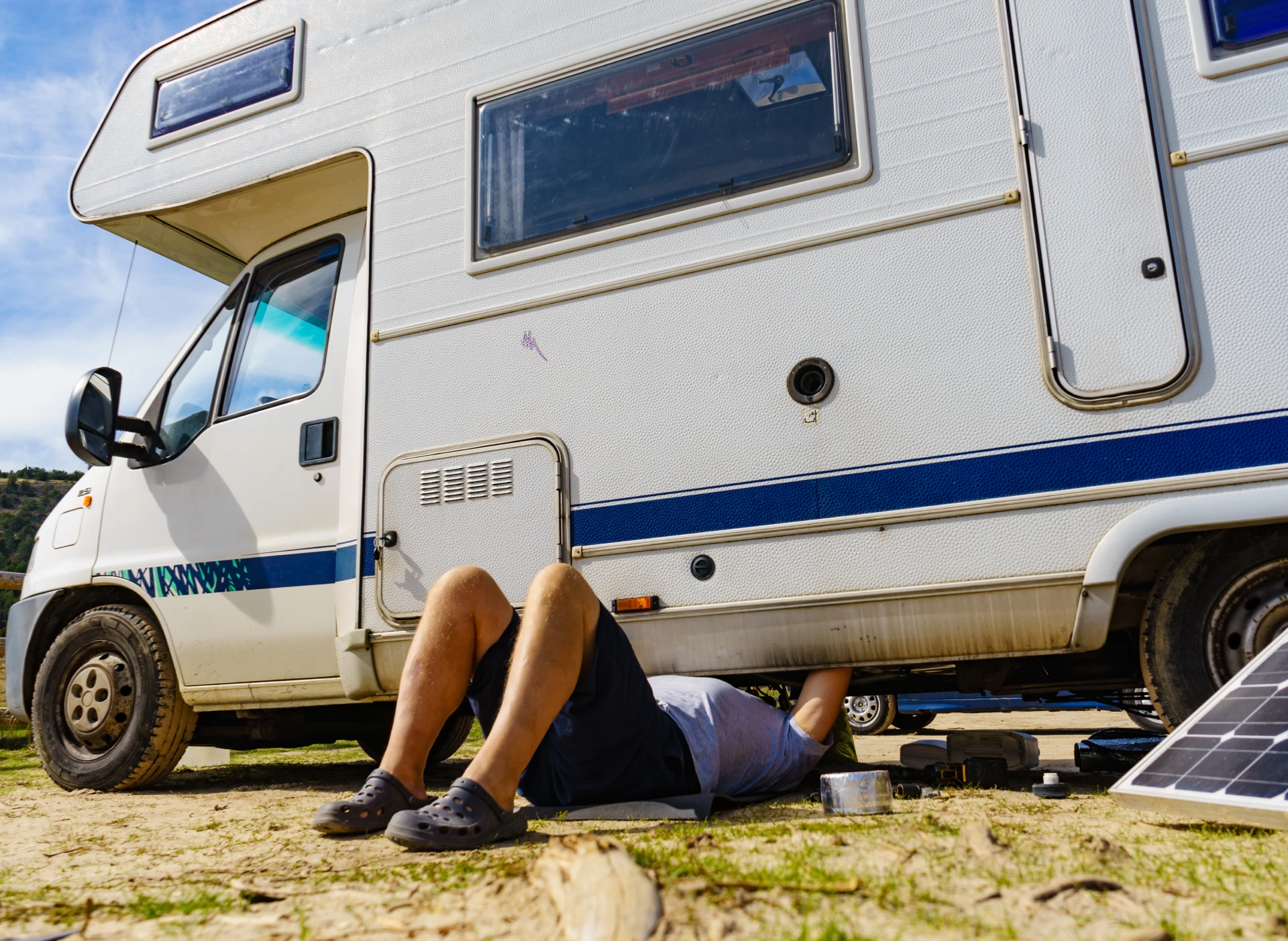 Person fixing under a camper van